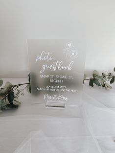 a clear acrylic sign sitting on top of a table next to some flowers