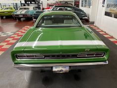 a green and white car in a garage with other cars on the wall behind it