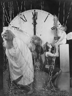 an old black and white photo of two men in front of a clock with streamers