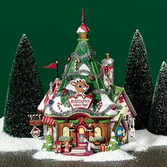 a christmas house with trees and decorations in the snow on a green background, surrounded by evergreens