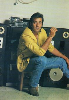 a man sitting on top of a chair in front of a stereo system with speakers behind him