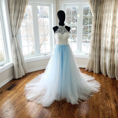 a blue and white wedding dress is on display in front of a window with drapes