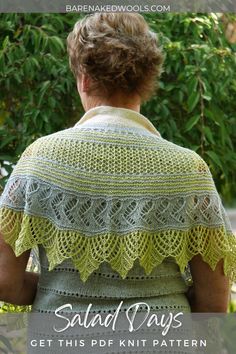 a woman wearing a green crochet shawl in front of some trees and bushes