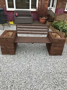 a wooden bench sitting on top of a gravel covered ground next to a potted plant