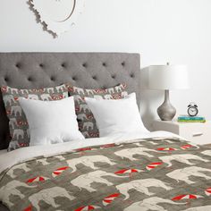 a bed with an elephant comforter on top of it next to a night stand