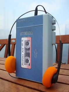 an old cassette player with headphones attached to it sitting on top of a wooden table