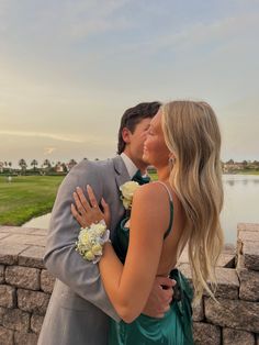 a man and woman kissing each other in front of a lake