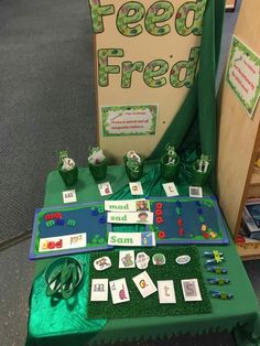 a green table topped with lots of cards and diced animals next to a sign that says feed free