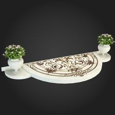 two white vases with flowers on top of a long table runner in the shape of an oval