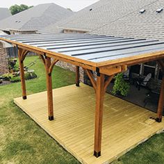 a covered patio with a table and chairs in the back yard next to a brick house