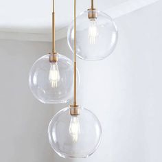 three clear glass globes hanging from a ceiling light fixture in a white walled room