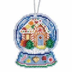 a beaded ornament with a house in the center and seashells on it