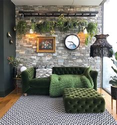 a living room filled with green furniture and lots of greenery on the brick wall