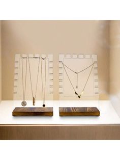 two necklaces are on display in a glass case, one is gold and the other is silver