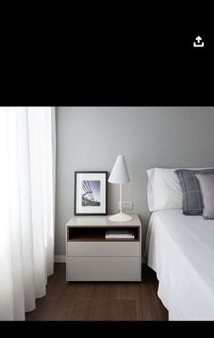 a white bed sitting next to a night stand with a lamp on top of it