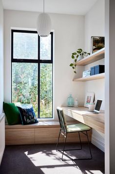 a window seat in front of a desk with a laptop computer on top of it