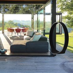 a couch sitting on top of a wooden floor next to a glass wall covered in windows