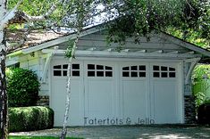 a white garage sitting in the middle of a lush green yard