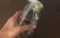 a person is holding a mason jar with some keys in it on a wooden table