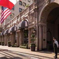 a man standing in front of a building with an american flag on the side of it