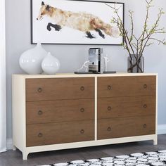 a dresser with two vases on top of it and a painting above the drawers