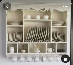 a white china cabinet filled with dishes and cups