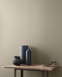 two black vases sitting on top of a wooden table