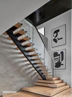 there is a stair case in this modern house with wood and glass railings on both sides