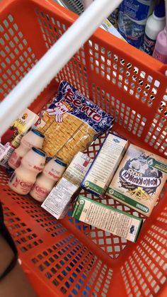 an orange shopping cart filled with snacks and milk in a grocery store or convenience store