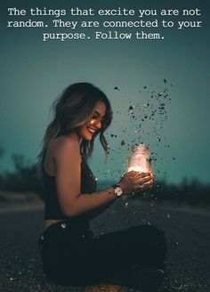 a woman sitting on the ground holding a jar filled with water and sparkles in it