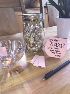 a jar filled with lots of candy sitting on top of a wooden table next to a cup