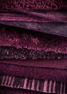 a pile of purple and black rugs stacked on top of each other in different colors