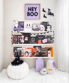 a white shelf filled with lots of books and halloween decorations on top of a white rug