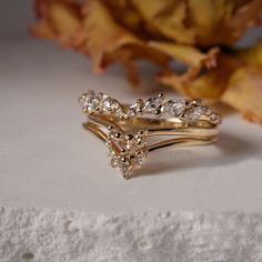 three gold wedding rings with diamonds on top and leaves in the background, sitting next to each other