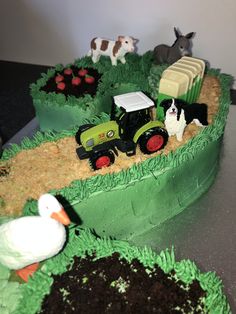 there is a cake with farm animals and tractors in the grass on top of it