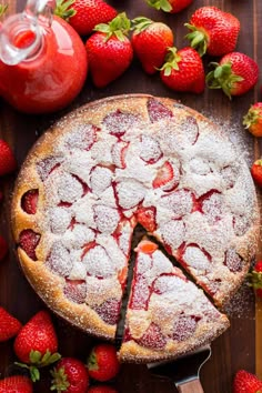 a strawberry pie with one slice cut out and strawberries around it on a wooden table