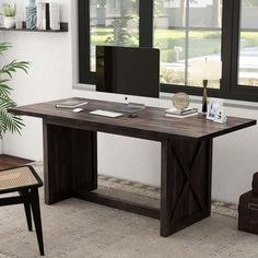 a computer desk with a monitor, keyboard and mouse on it in front of a window