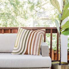 a white couch sitting on top of a wooden floor next to a potted plant