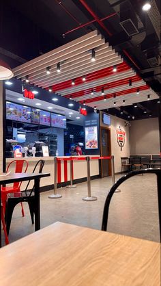 the inside of a fast food restaurant with red and white striped ceilinging, tables and chairs