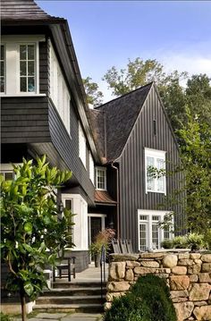 a black house with white windows and stone steps leading up to the front door area