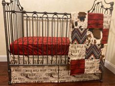 a metal crib with a red blanket on it and a cow print bedding