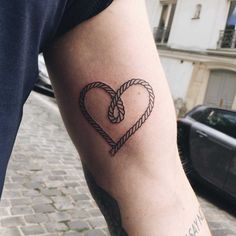 a man with a tattoo on his arm holding a rope in the shape of a heart