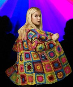 a woman in a colorful crochet granny granny afghan is standing with her hands on her hips