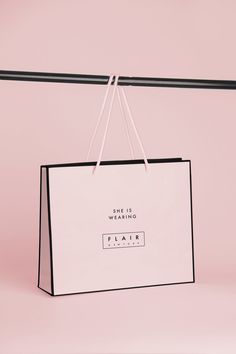 a white shopping bag hanging on a pink background with the words, she is going to flat