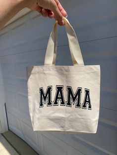 a person holding up a bag with the word mam on it in front of a garage door