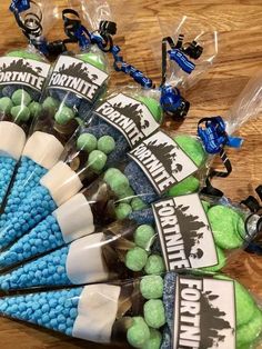 several lollipops wrapped in plastic bags on a wooden table with blue and green candies