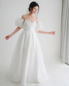 a woman in a white wedding dress posing for the camera with her arms spread out