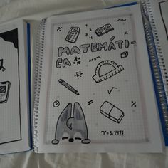 two notebooks with drawings on them sitting next to each other