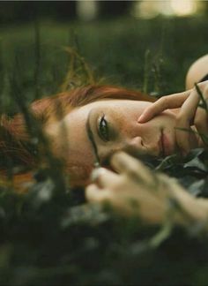 a woman laying in the grass with her eyes closed