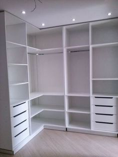 an empty closet with white shelves and drawers